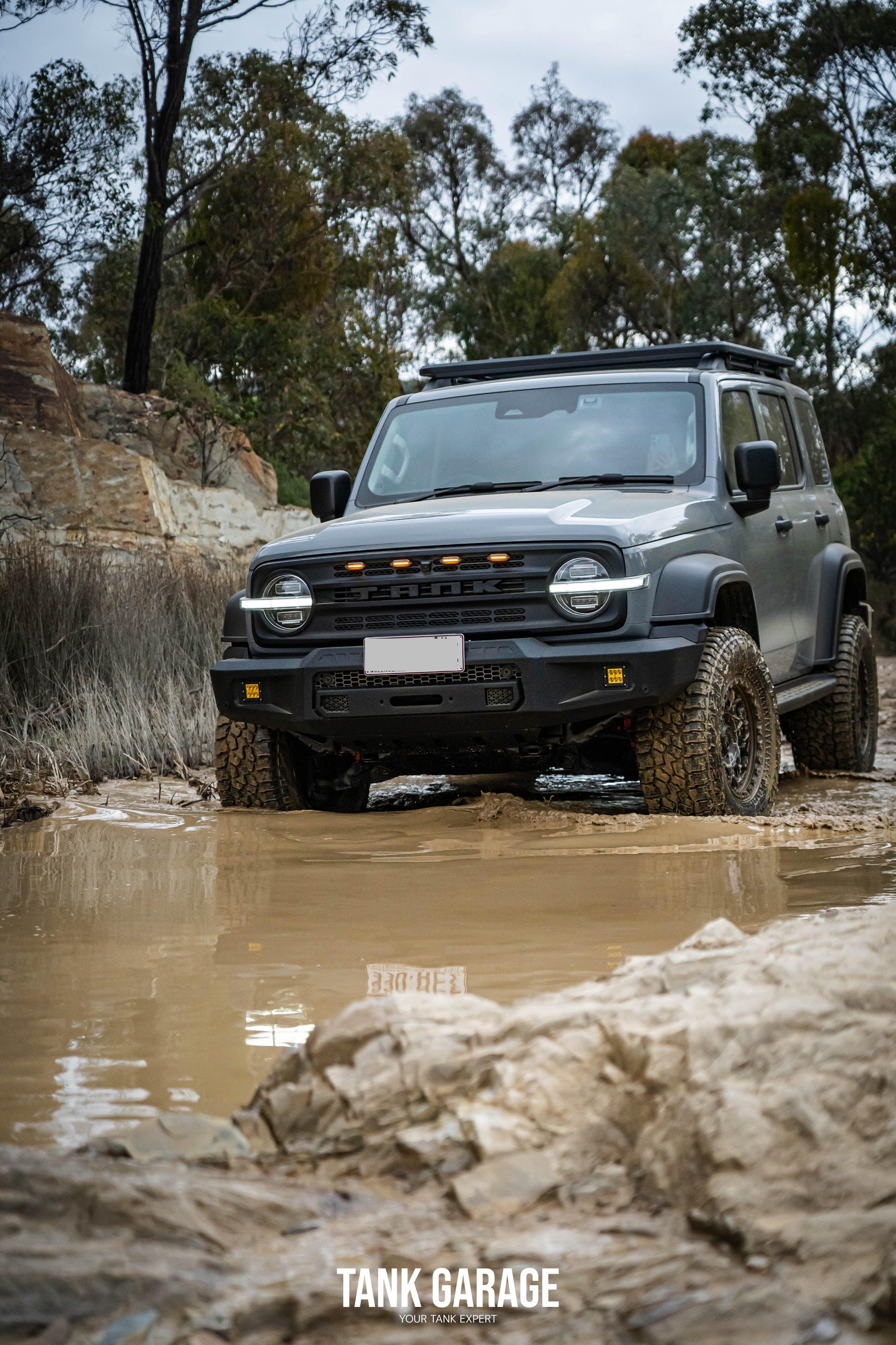 The grey Tank 300 comes with top off-road upgrades, like a TKG roof rack for extra storage, the bold War God front grille, and the tough "Gulfstream" front bumper. Its muddy off-road setting shows off its strength and rugged design.